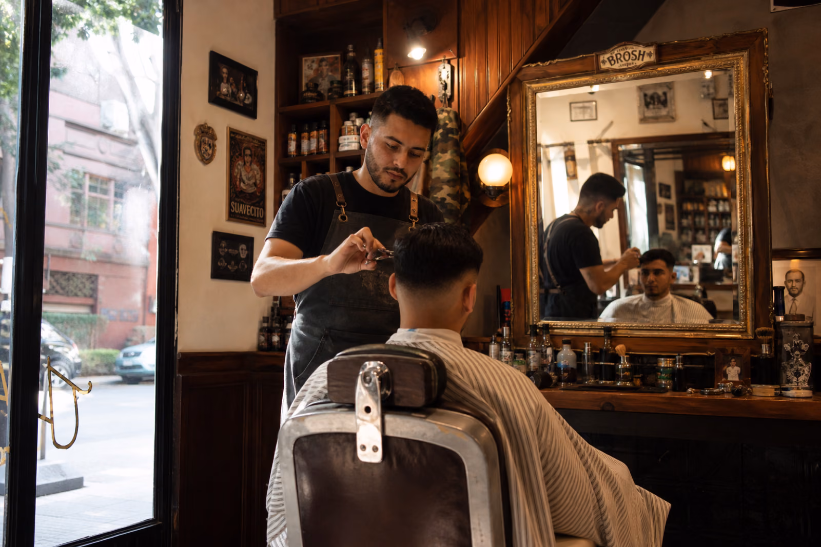 Cliente en silla de barbero con espejo de fondo, barbería en Roma Norte